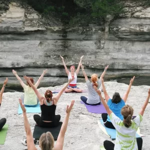 women practicing yoga on riverbank